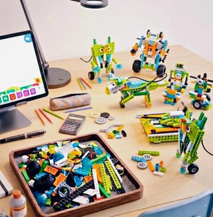 Навчальна зона з роботами WeDo 2.0, планшетом та деталями конструктора на дерев'яному столі