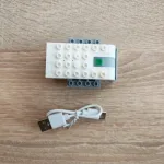 Перезаряджувальний Bluetooth хаб для робототехніки WeDo 2.0 (вигляд зверху) з USB-кабелем на дерев'яній стільниці