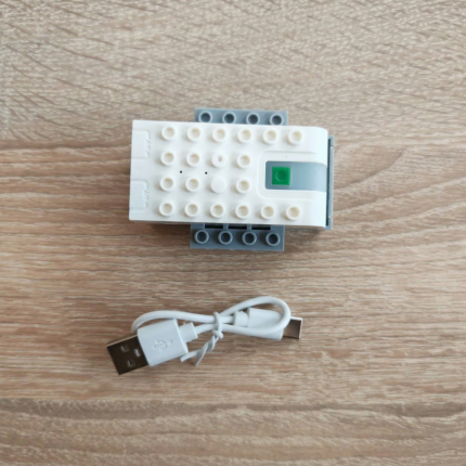 Перезаряджувальний Bluetooth хаб для робототехніки WeDo 2.0 (вигляд зверху) з USB-кабелем на дерев'яній стільниці