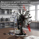 Демонстрація конструктора зірчастого двигуна ззаду на дерев'яному столі із блоком живлення, шестернями та рекламним написом українською мовою про високоточні деталі