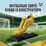 Зібраний конструктор золота бутса на чорній підставці посеред футбольного стадіону з написом Футбольне свято кубок із конструктора
