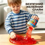 Хлопчик виливає безпечний желейний слайм зі стаканчика для створення траси ігрового слайм-треку з машинкою